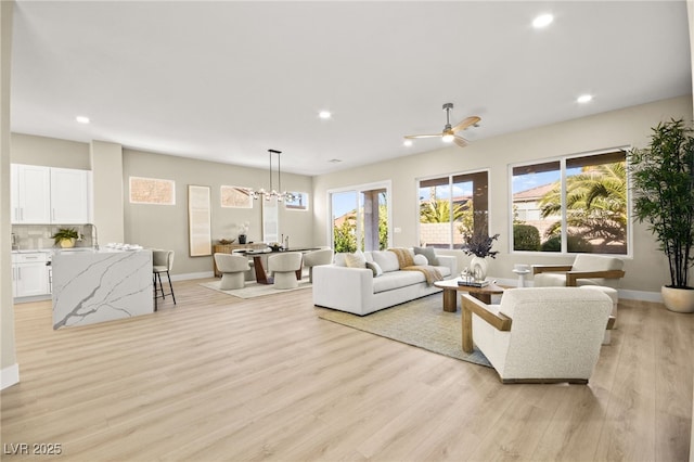 living room with a ceiling fan, recessed lighting, baseboards, and light wood finished floors