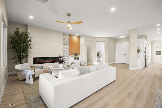 living room featuring baseboards, a ceiling fan, a tile fireplace, light wood-style floors, and recessed lighting