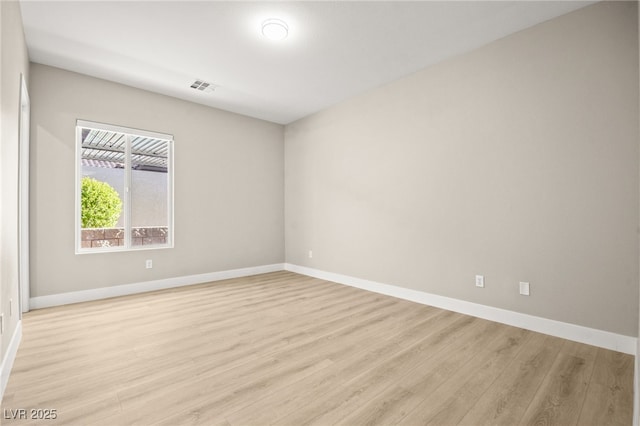 spare room featuring visible vents, light wood-style flooring, and baseboards