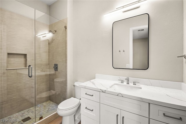 bathroom featuring toilet, a shower stall, and vanity