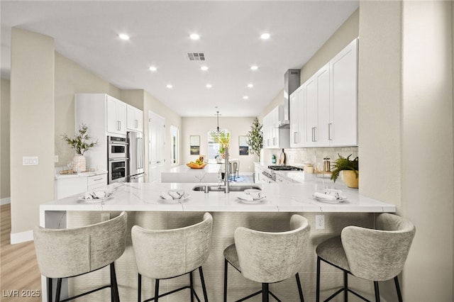 kitchen featuring a peninsula, tasteful backsplash, visible vents, and white cabinets