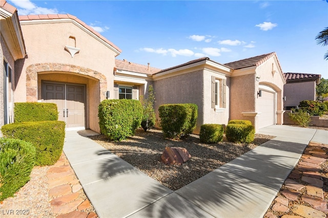 view of front of property with an attached garage, driveway, and stucco siding