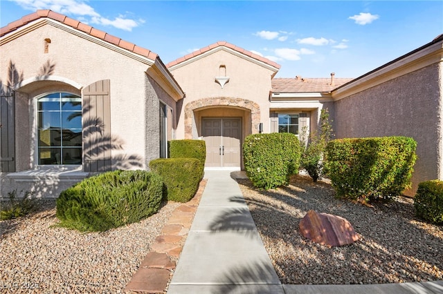 doorway to property with a tile roof and stucco siding