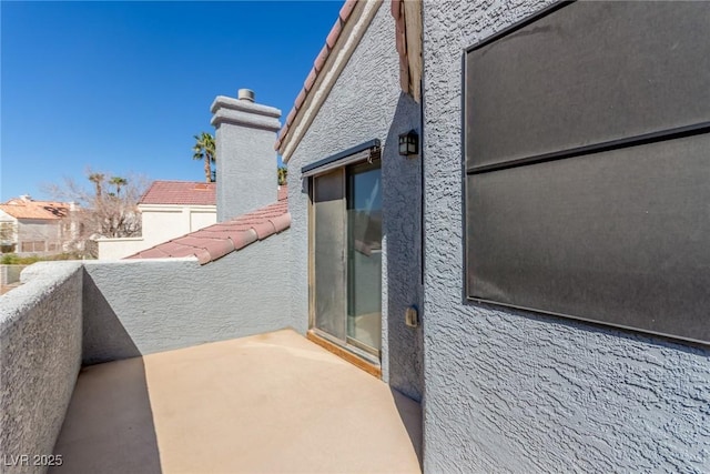 exterior space featuring a tiled roof, a balcony, and stucco siding