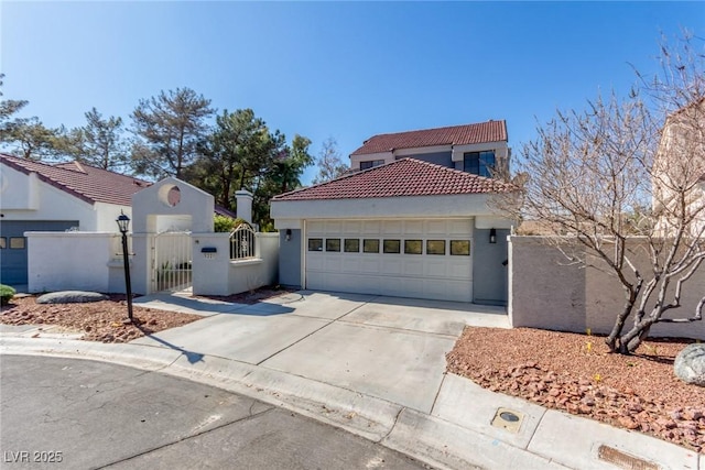 mediterranean / spanish-style house featuring a fenced front yard, an attached garage, a tile roof, concrete driveway, and a gate