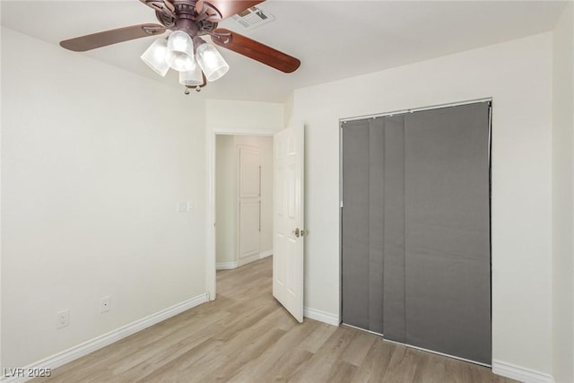 unfurnished bedroom featuring a closet, visible vents, light wood-style flooring, ceiling fan, and baseboards