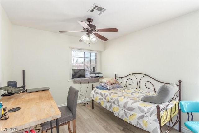 bedroom featuring a ceiling fan, wood finished floors, visible vents, and baseboards