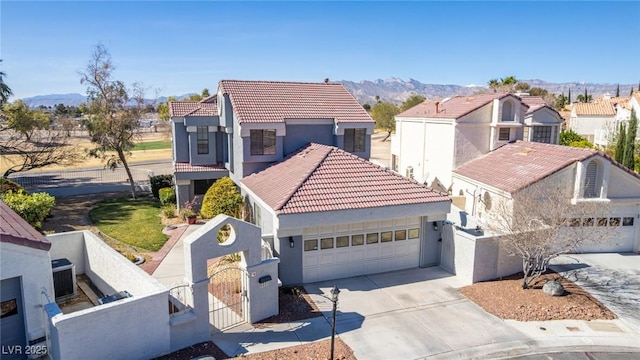 mediterranean / spanish-style house featuring a fenced front yard, a tile roof, concrete driveway, a gate, and a garage