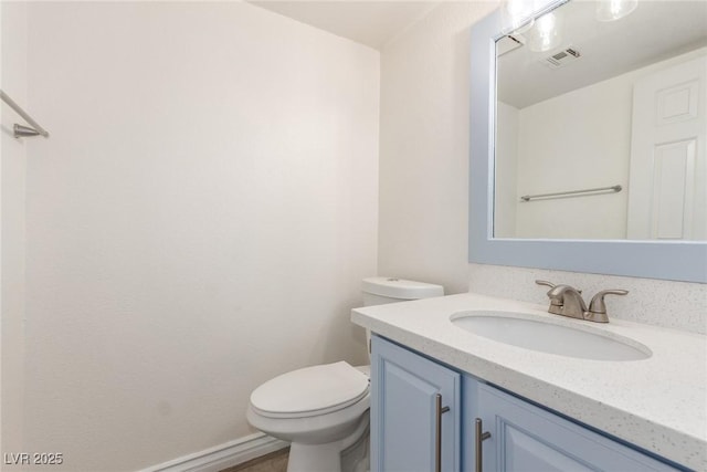 bathroom with toilet, vanity, and visible vents