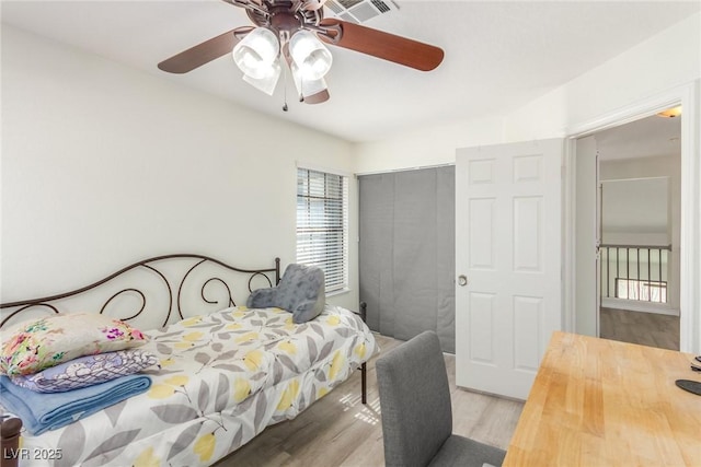 bedroom featuring ceiling fan, a closet, visible vents, and wood finished floors