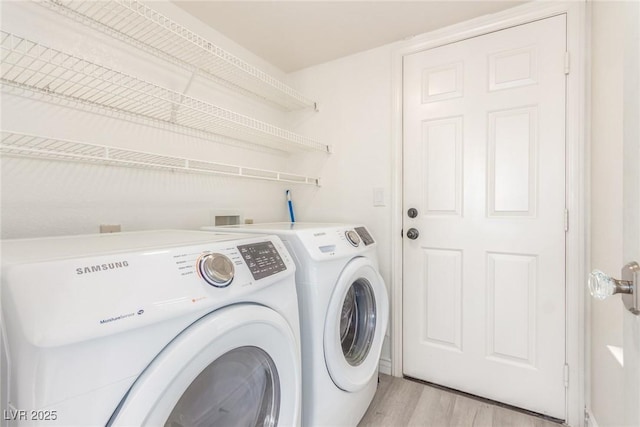 clothes washing area with laundry area, light wood-style flooring, and washing machine and clothes dryer