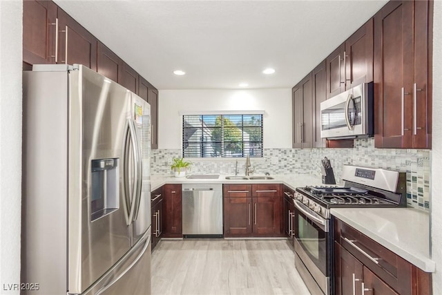 kitchen with light countertops, appliances with stainless steel finishes, a sink, and decorative backsplash