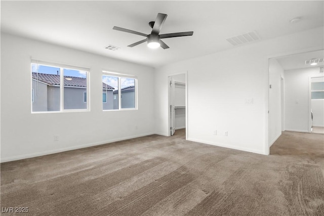 carpeted spare room featuring visible vents, ceiling fan, and baseboards