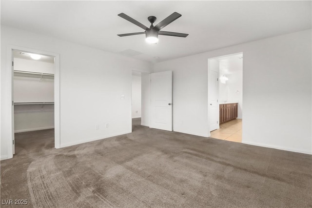 unfurnished bedroom featuring ceiling fan, connected bathroom, carpet flooring, a spacious closet, and a closet