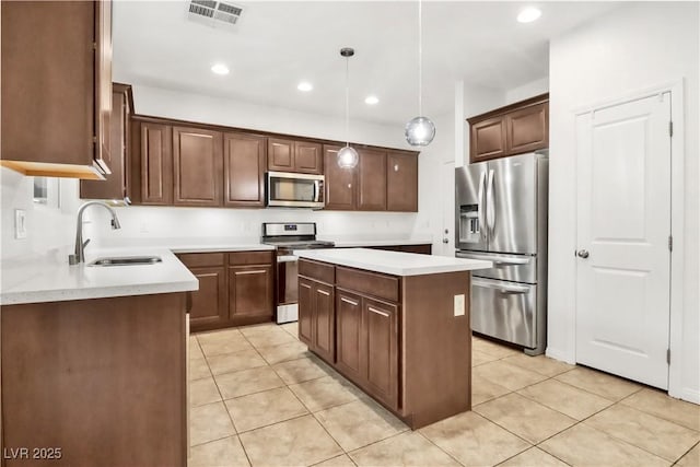 kitchen with visible vents, a center island, light countertops, stainless steel appliances, and a sink