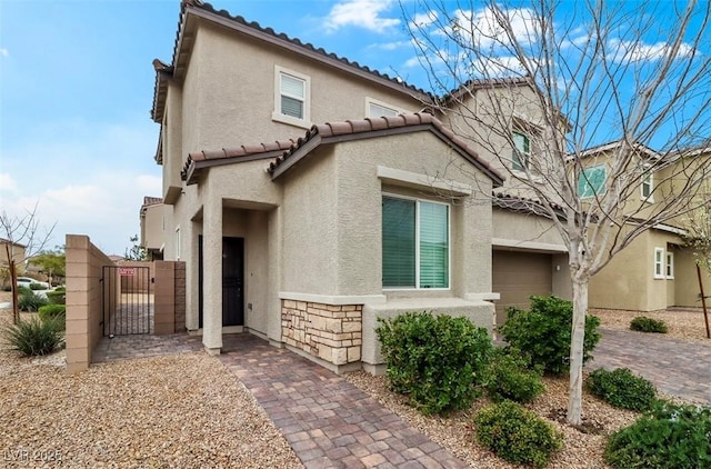 mediterranean / spanish-style home with stone siding, a tiled roof, a gate, and stucco siding