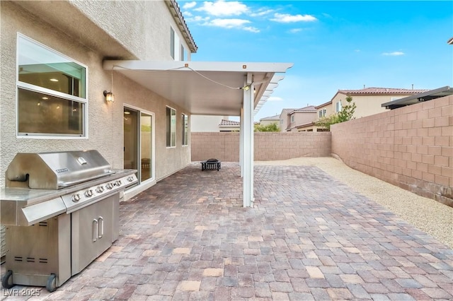 view of patio with an outdoor kitchen, a fenced backyard, and grilling area