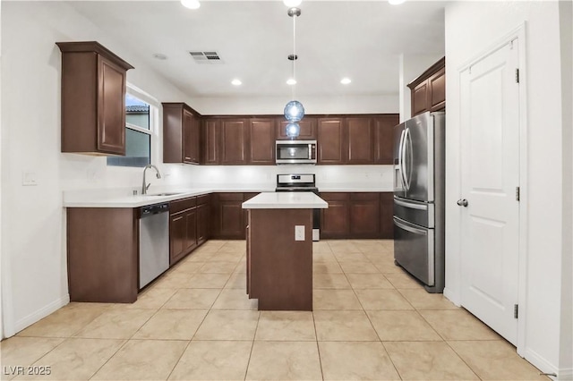 kitchen featuring visible vents, a kitchen island, appliances with stainless steel finishes, light countertops, and a sink