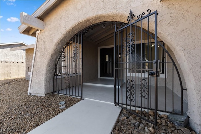 doorway to property featuring a gate, fence, and stucco siding