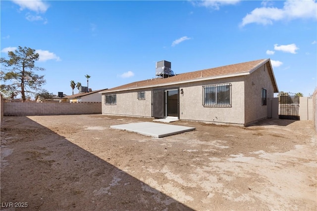 rear view of property with central AC, a patio area, a fenced backyard, and stucco siding