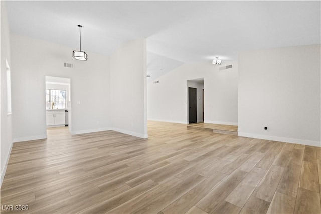 unfurnished room featuring light wood-type flooring, visible vents, and lofted ceiling