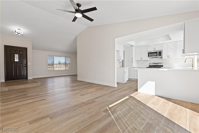 unfurnished living room with lofted ceiling, light wood-style floors, ceiling fan, and baseboards