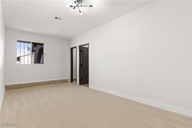 empty room with light carpet, baseboards, visible vents, and a notable chandelier