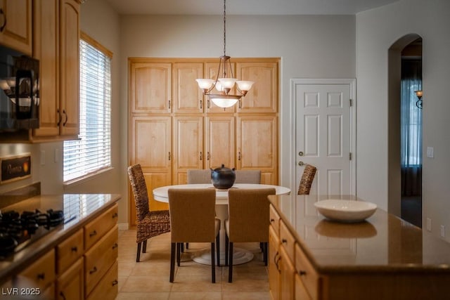 dining space featuring light tile patterned floors, plenty of natural light, arched walkways, and an inviting chandelier