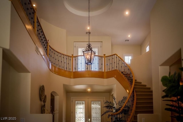 entryway featuring a chandelier, visible vents, a towering ceiling, and stairs