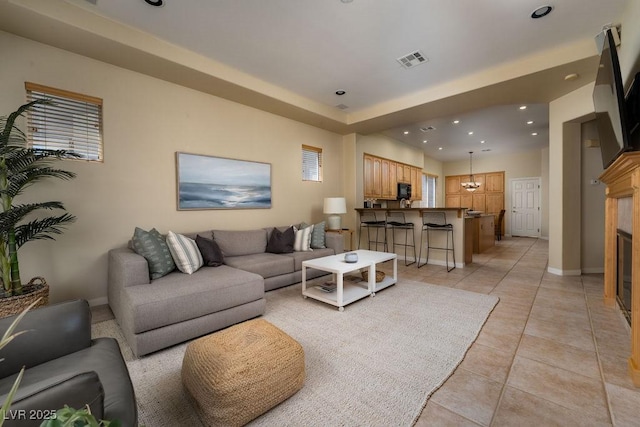 living area with light tile patterned floors, recessed lighting, visible vents, a glass covered fireplace, and baseboards