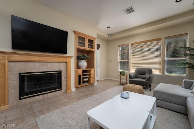 living area with light tile patterned floors, baseboards, a fireplace, and visible vents