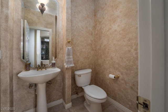 bathroom with baseboards, a sink, toilet, and tile patterned floors