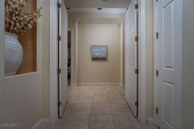 corridor featuring light tile patterned flooring and baseboards