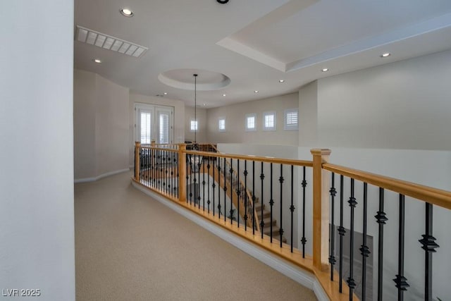 hall with baseboards, visible vents, a tray ceiling, and recessed lighting