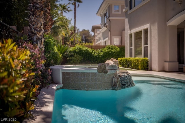 outdoor pool featuring fence and a hot tub