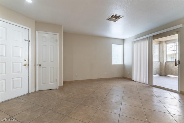 unfurnished room featuring baseboards, visible vents, a wealth of natural light, and light tile patterned flooring