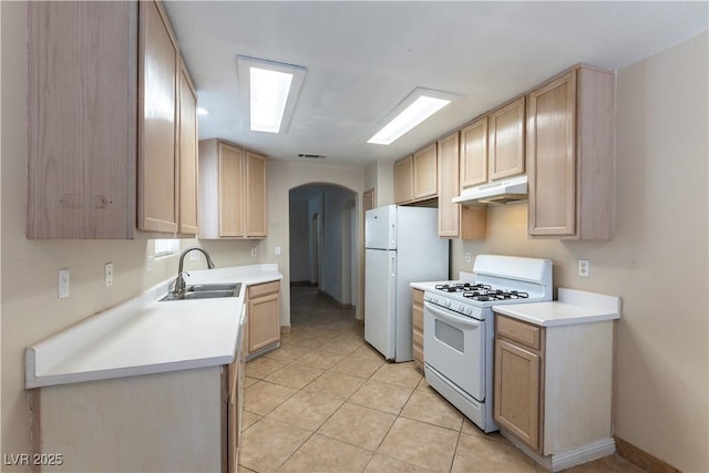 kitchen with arched walkways, light brown cabinets, under cabinet range hood, white appliances, and a sink