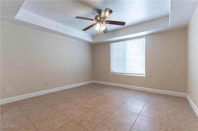 unfurnished room with light tile patterned floors, ceiling fan, baseboards, and a raised ceiling