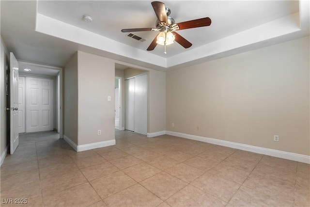 empty room featuring light tile patterned floors, baseboards, visible vents, a raised ceiling, and ceiling fan