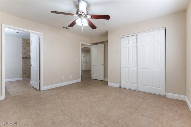 unfurnished bedroom featuring arched walkways, a closet, visible vents, and baseboards