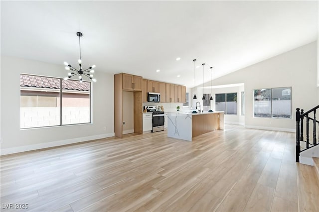 kitchen featuring light wood-style flooring, open floor plan, light countertops, stainless steel appliances, and a sink