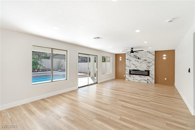 unfurnished living room with recessed lighting, a high end fireplace, baseboards, a ceiling fan, and light wood-type flooring