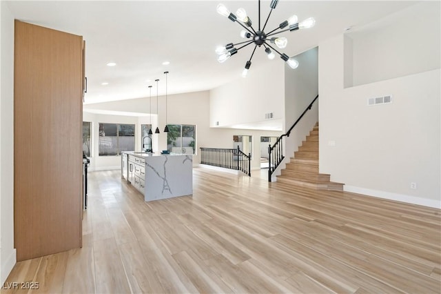 interior space featuring visible vents, light wood-style flooring, an inviting chandelier, high vaulted ceiling, and stairs