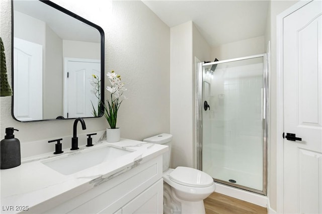 full bathroom with toilet, a shower stall, wood finished floors, and vanity