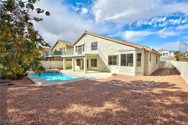 rear view of property featuring a fenced in pool, a patio, stucco siding, a balcony, and a fenced backyard