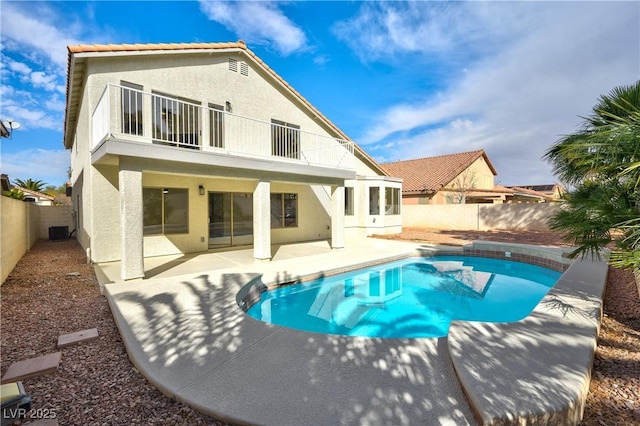 back of property with stucco siding, central AC unit, a patio area, a balcony, and a fenced backyard