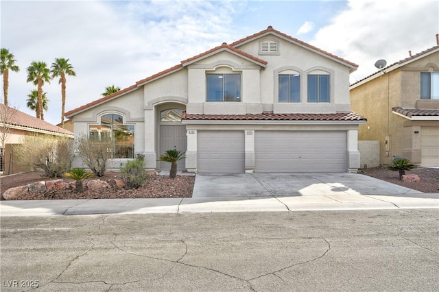 mediterranean / spanish home with a garage, concrete driveway, a tiled roof, and stucco siding