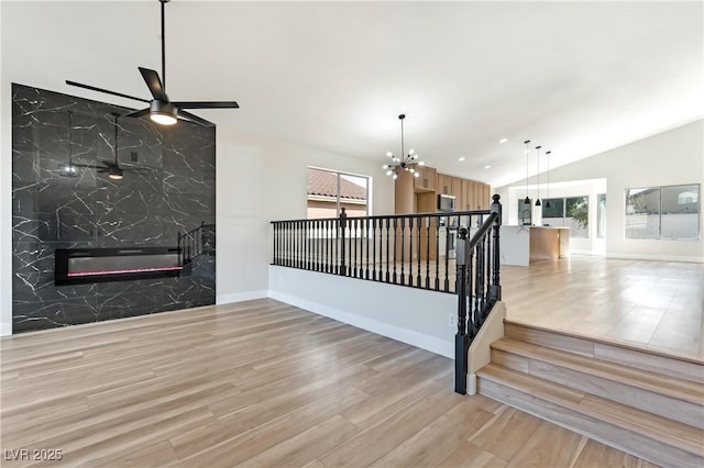 interior space featuring lofted ceiling, a fireplace, baseboards, and wood finished floors