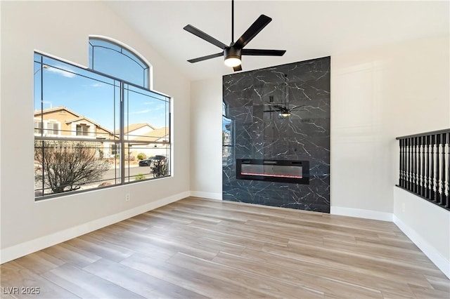 unfurnished living room with a ceiling fan, a fireplace, baseboards, and wood finished floors