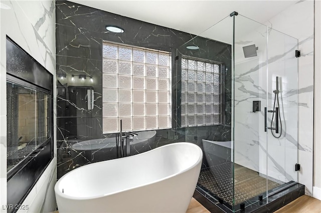 full bath featuring a freestanding tub, tile walls, and a marble finish shower